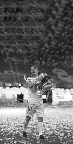 a young boy holding a soccer ball in his right hand while standing on a field