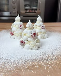 several small white cakes sitting on top of a wooden table covered in powdered sugar