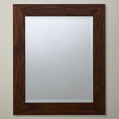 a mirror hanging on the wall above a sink in a bathroom with a wooden frame