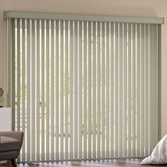 a bed sitting next to a window with wooden blinds on top of it's sides