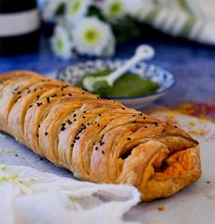 a croissant is sitting on a table next to a bowl with some sort of sauce