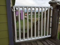 a white railing on a wooden deck in front of a green house