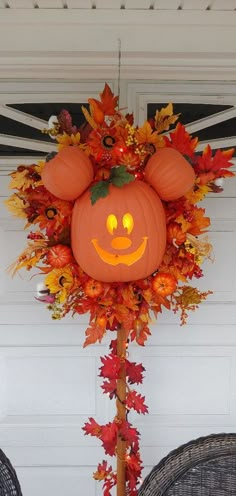 a mickey mouse pumpkin head on top of a pole with leaves around it and an orange pumpkin in the middle