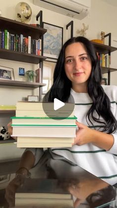 a woman sitting at a table with stacks of books