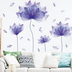 a living room with white furniture and purple flowers painted on the wall behind it,