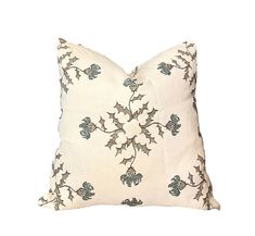 a white pillow with blue and green holly designs on the front, sitting on a white background