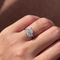 a woman's hand with a diamond ring on her finger, showing the center stone