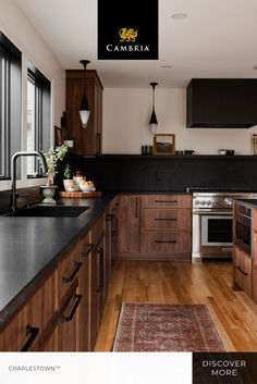 a kitchen with wooden cabinets and black counter tops, along with a rug on the floor