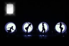 the silhouettes of dancers are projected in circular glass circles on a black background with light coming from behind them