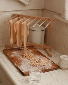 pasta being cooked on a cutting board in a kitchen with utensils hanging from the rack