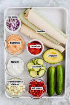 the ingredients for this sandwich include cucumbers, tomatoes, onions, red onion, and hummus