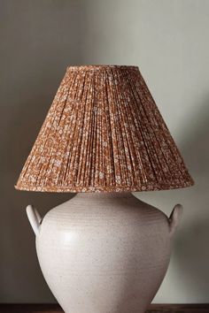 a white vase with a brown shade on it sitting on top of a wooden table