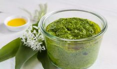 a jar filled with green sauce next to flowers