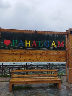 a wooden bench in front of a sign that says i love pahlogam