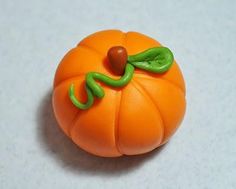 an orange plastic pumpkin with a green leaf on it's head and eyes, sitting on a white surface