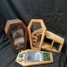 three wooden boxes with different types of items in them on a black cloth covered background