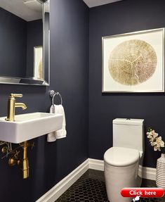 a white toilet sitting next to a sink in a bathroom under a framed art piece