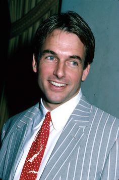 a man in a suit and tie smiling for the camera