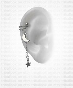 an ear with a chain attached to it and a crescent charm hanging from the side