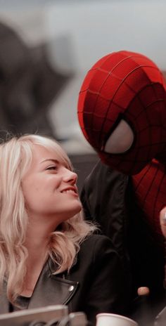 a woman with blonde hair and a spider man mask on, sitting next to her