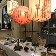 three lamps hanging over a table with plates and bowls on it