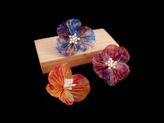 **This product is made to order, please allow 3-5 days before dispatch.** An intricate and colourful marbled silk flower brooch, created with hand-dyed organza silk fabric of a marble pattern with gold streaks. The flowers are made with the Tsumami-zaiku technique, and are embellished with millinery stamens. Each flower is mounted onto a silver plated brooch and it comes in three colour combinations: pink and purple, blue and purple, orange and pink. A wonderful complement for a chic, smart casual outfit. Perfect for every day of the week. The brooch is made with extra lightweight, translucent organza silk fabric, which was carefully cut and hand-dyed with a marble pattern. The fabric pieces were intricately folded to create delicate details, which were then assembled into a flower to crea Three Color Combinations, Japanese Craft, Hand Dyed Silk, Orange And Pink, Japanese Crafts, Silk Dyeing, Silk Flower, Floral Jewellery, Delicate Details