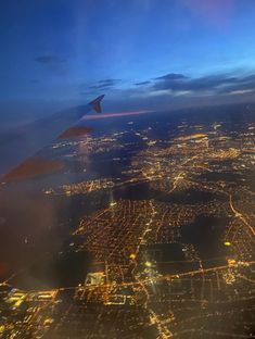 an airplane wing flying over a city at night