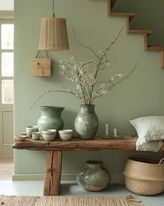 a wooden table topped with vases next to a stair case filled with flowers and candles