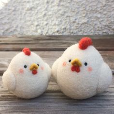 two small white chickens sitting on top of a wooden table next to eachother