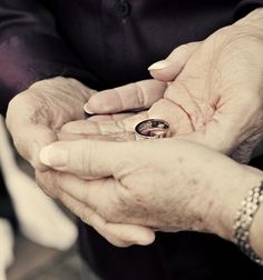 an older couple holding their wedding rings in their hands