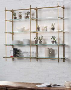 the shelves are filled with plants and vases on top of each shelf in front of a brick wall