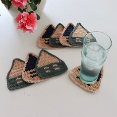 four crocheted coasters and a glass on a white table with pink flowers