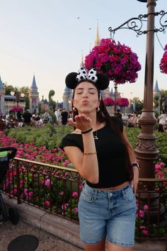 a woman standing in front of a street light with minnie mouse ears on her head