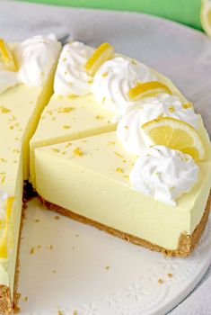 a white plate topped with a cheesecake covered in whipped cream and sliced lemons