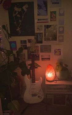 a guitar sitting on top of a table next to a plant in a room filled with pictures