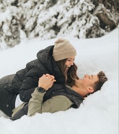 a man and woman laying in the snow