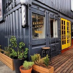 an outside view of a store with potted plants on the front and yellow doors