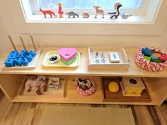 a wooden table topped with different types of toys and decorating items next to a window