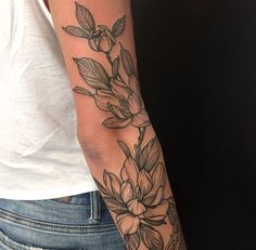 a woman's arm with flowers and leaves tattooed on the side of her arm