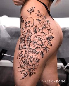 a woman's thigh with flowers and a skull on the side, in black and white