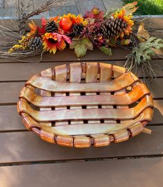 a wooden bowl sitting on top of a table next to some pine cones and flowers