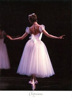 the back of a ballerina's dress with her arms stretched out and hands outstretched