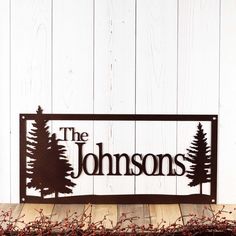 a metal sign that says the johnsons with trees in it on a wooden table