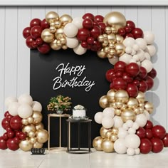 a happy birthday sign surrounded by balloons and other decorations on a table in front of a wall