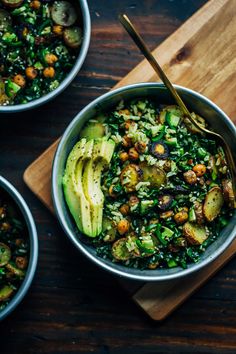 three bowls filled with food on top of a wooden cutting board