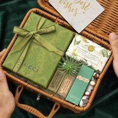 two hands holding a wicker basket filled with assorted gift items and greeting cards