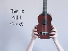 a woman holding up a ukulele with the words this is all i need