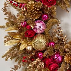 red and gold christmas decorations hanging on the wall with pine cones, berries, and leaves