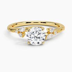 a yellow gold engagement ring with an oval cut diamond in the center and side stones