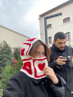 a woman wearing a red and white crocheted hat while holding a cell phone